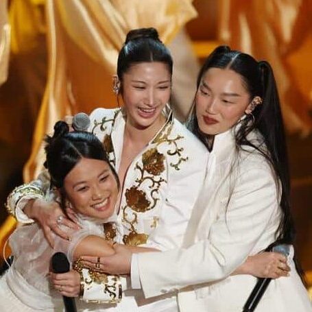 KPop Demon Hunters singers REI AMI, EJAE, and Audrey Nuna embrace after Oscars "Golden" performance.