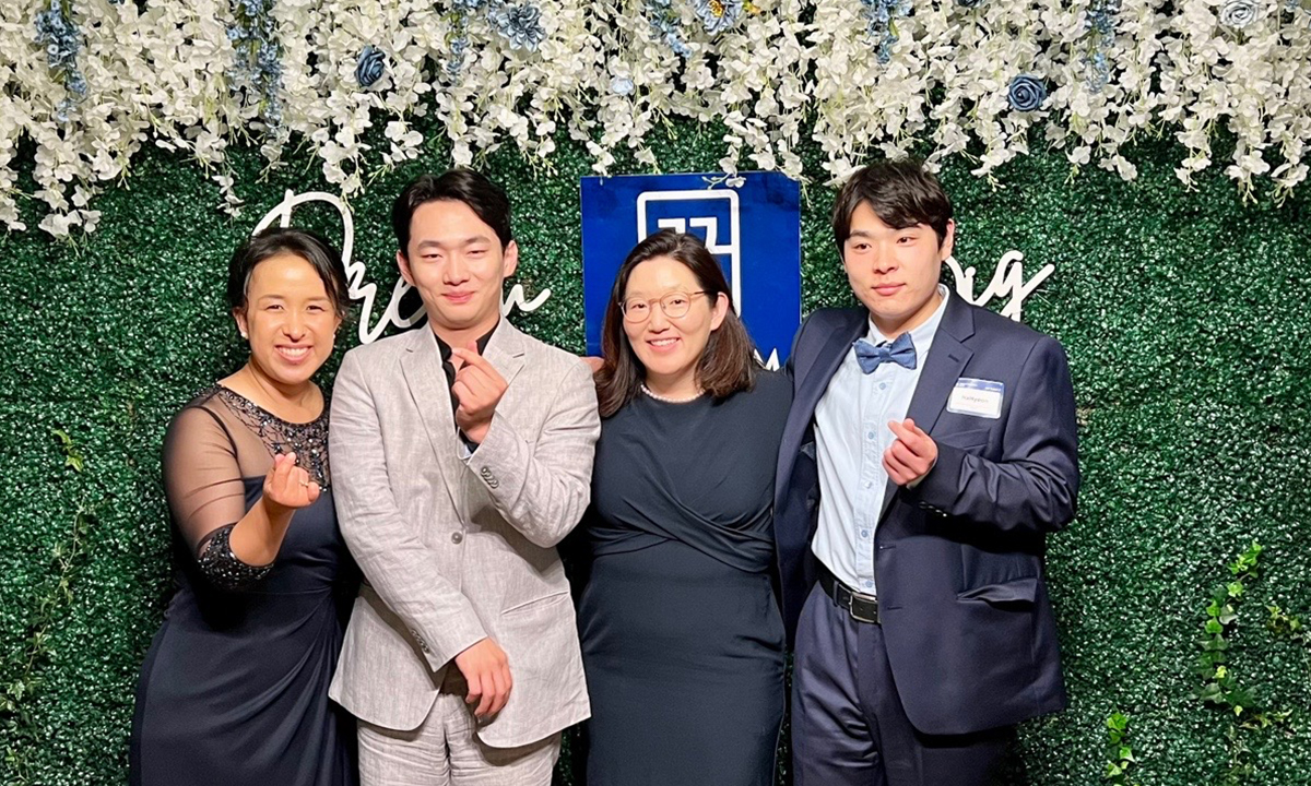 Two women and two KKOOM supported college graduates pose in front of KKOOM’s Dream Big Gala backdrop.