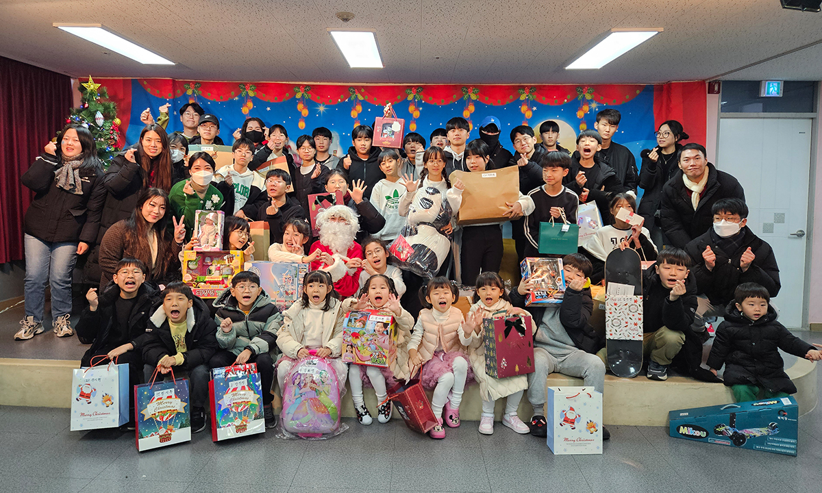 A large group of volunteers and children take a photo with Santa along with their new Christmas presents.
