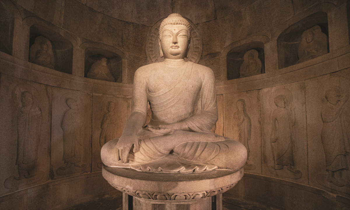 A rare close up image of the stone Buddha sitting in Gyeongju’s Seokguram Grotto. It rests in a circular and hollow cave filled with other statues.