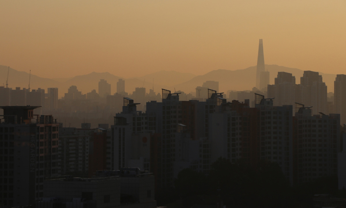 A dark silhouette city landscape covered in the air pollution haze of yellow dust.