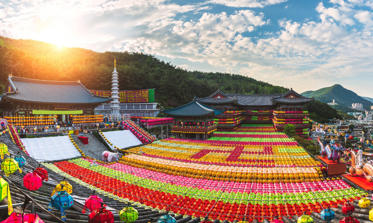 A huge buddhist temple with thousands of colorful pattern lanterns that hang within the buildings creating a blanket effect.