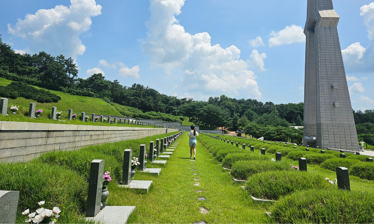 An image of person walking in the distance within the rows of memorial mounds and headstones of those who lost their lives in the Gwangju Uprising in South Korea.