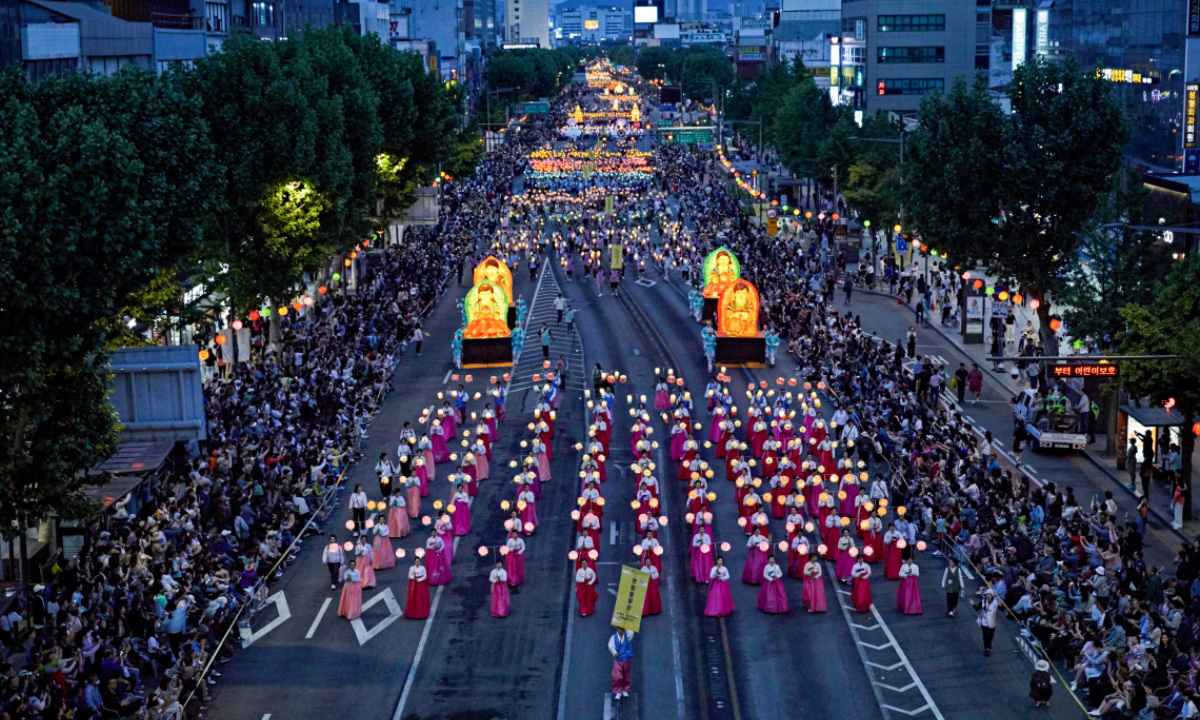 An aerial shot of the Seoul Lotus Lantern parade at night where thousands of people line the streets to watch the enormous parade.