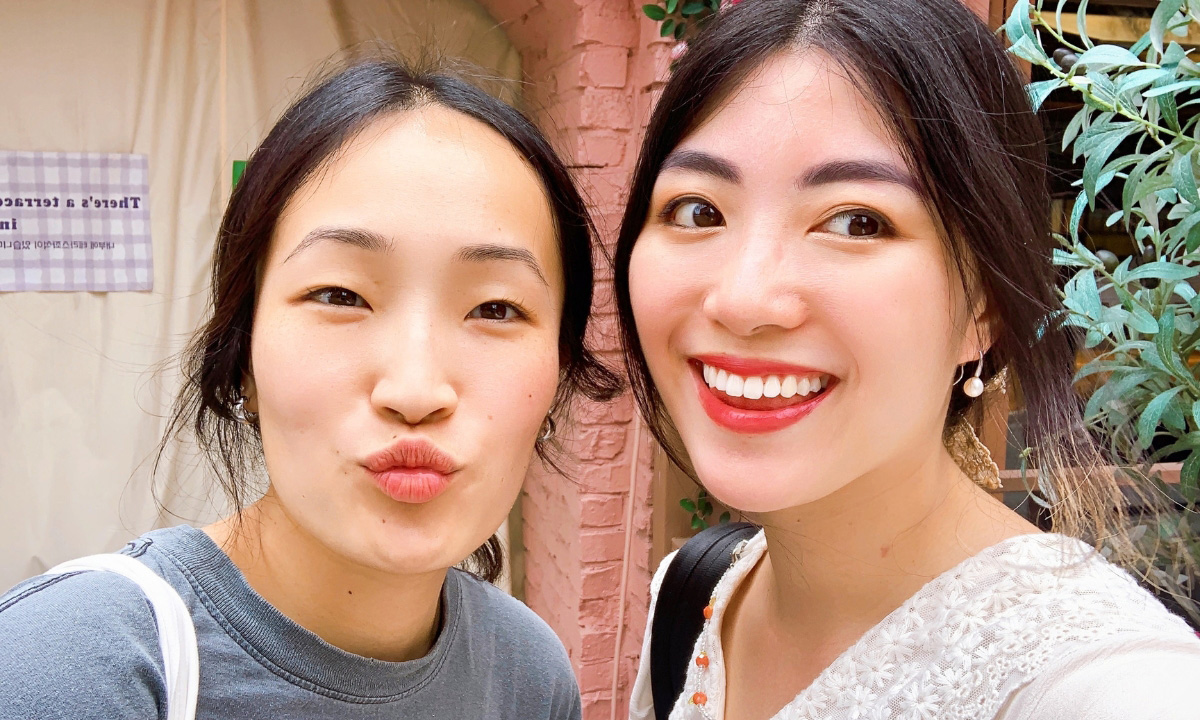 Two asian women take a selfie shot with smiles and silly faces.