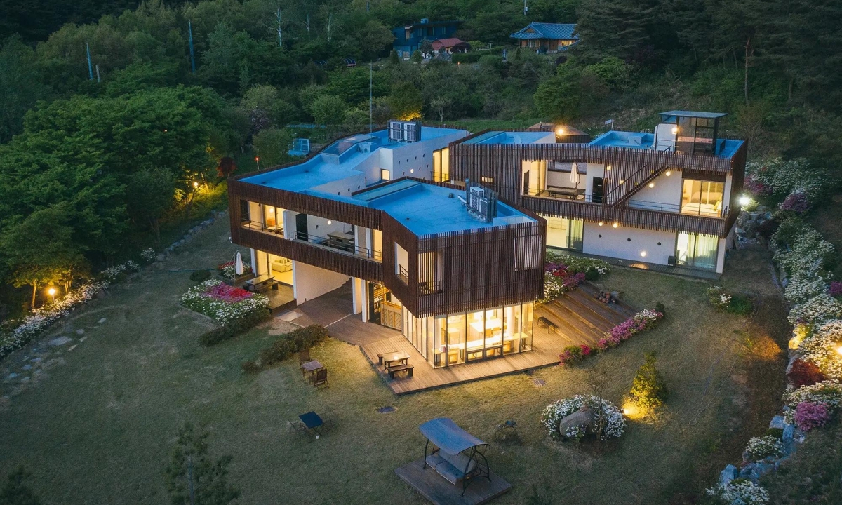 A beautiful overhead view of Soohwarim Pension nestled into a hill and garden backdrop at dusk as the light starts to come on.