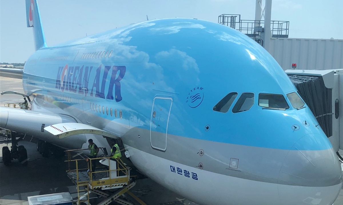 A parked view of a Korean Air plane from the airport waiting area, as crew are seen checking on the plane’s various compartments.