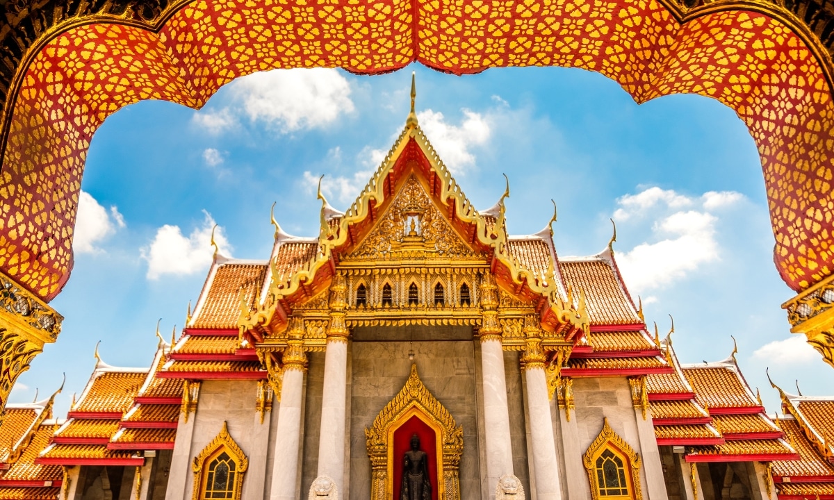 Looking up at the intricately detailed ceiling and roof of the Benchamabophit Dusitvanaram Buddhist Temple in Bangkok, Thailand.