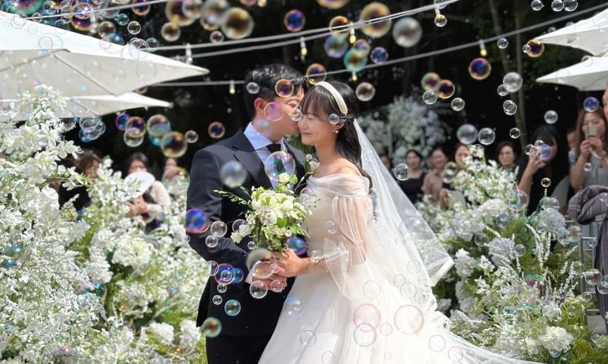 Bride and groom embracce while walking through bubbles during modern Korean wedding exit.