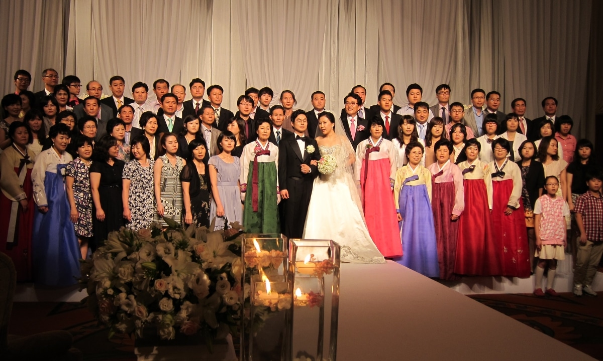 A large group photo of a family taking a photo on center stage during a modern Korean wedding.