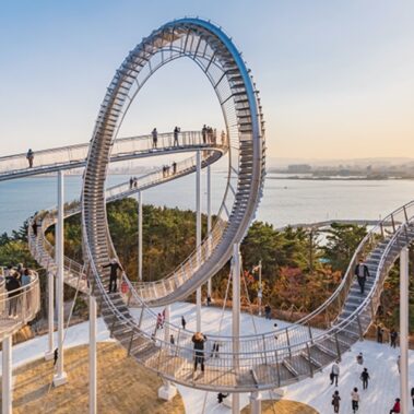 A beautiful side view of Pohang's Space Walk with a clear day and blue ocean behind it.
