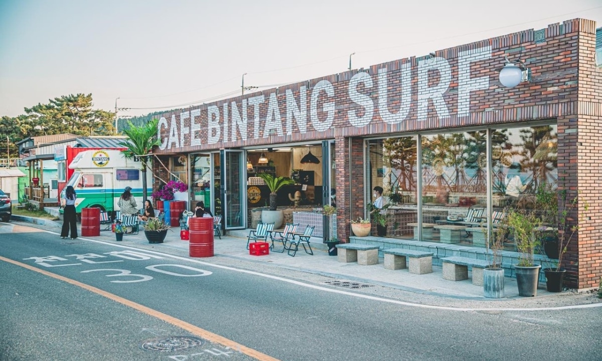 A surf-themed café in Pohang with palm trees, neon signs, and a laid-back vibe.
