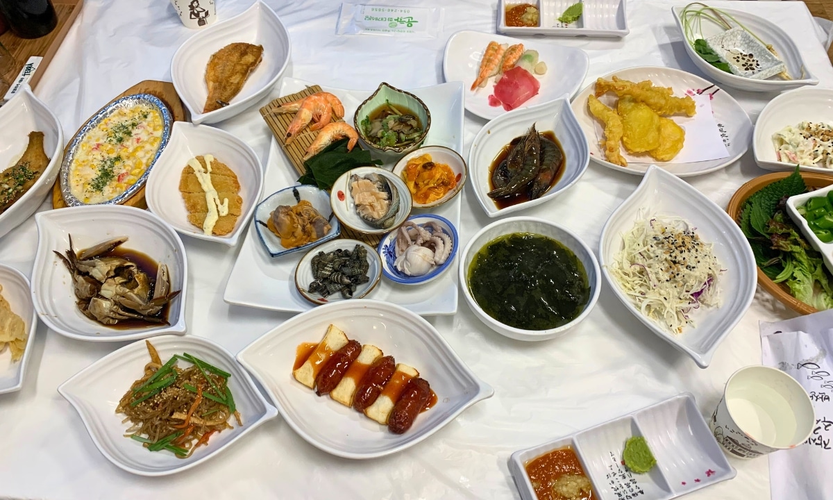 A full table spread with assorted seafood and side dishes from a local market.