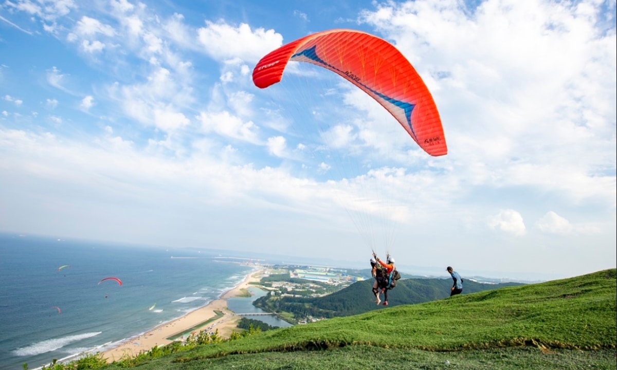 A paraglider soaring above the coastline and ocean in Pohang.