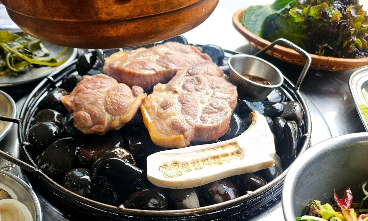 Sizzling grilled meat on hot stones with Korean-style side dishes.