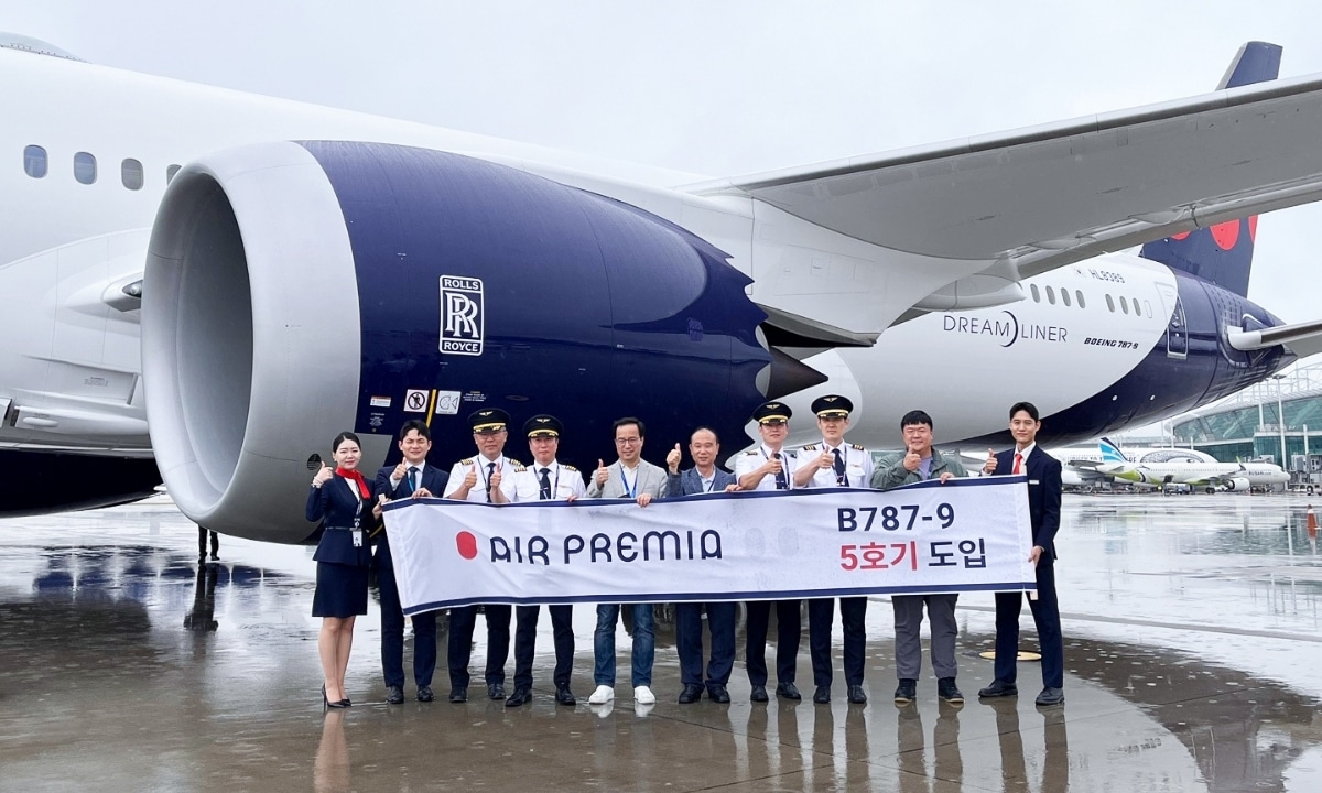 Air Premia airline staff posing in front of a parked aircraft, showcasing team culture and branding.