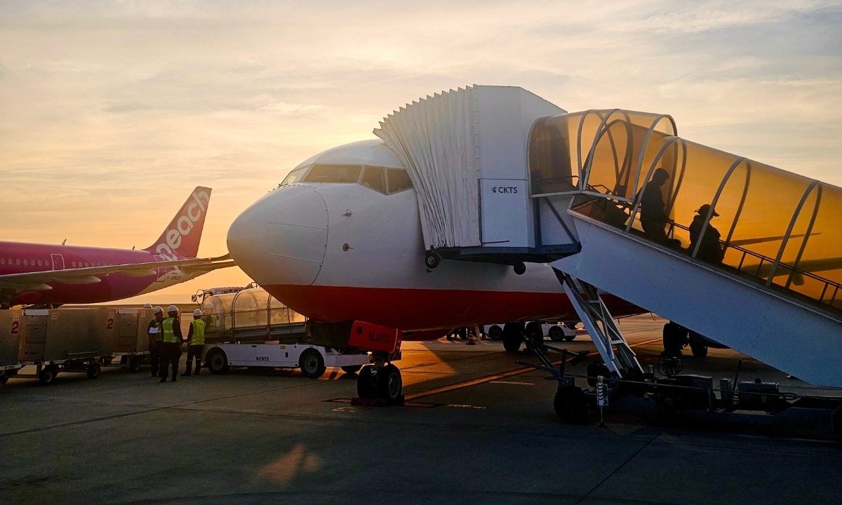 A commercial jet parked at the gate during sunset, illustrating the operational side of airlines at airports.