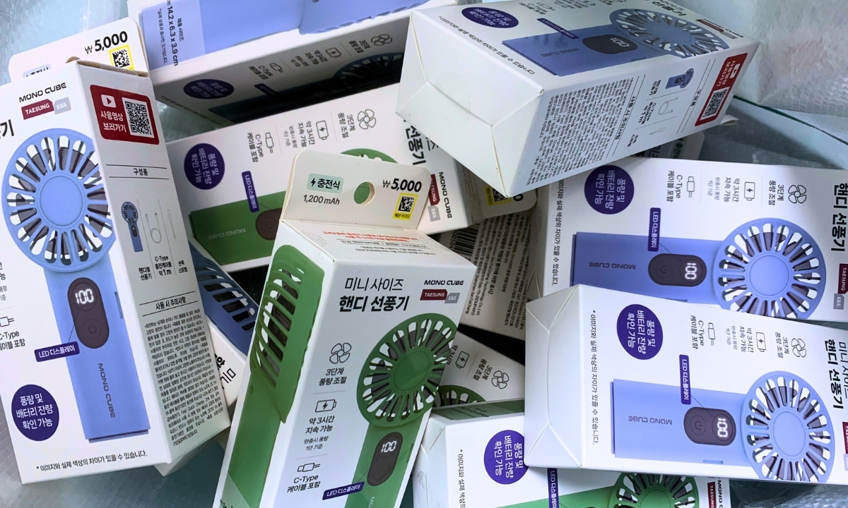 Display of colorful blue and green handheld and electric fans in a Korean store, commonly used to beat the heat during hot and humid Korean summer days.