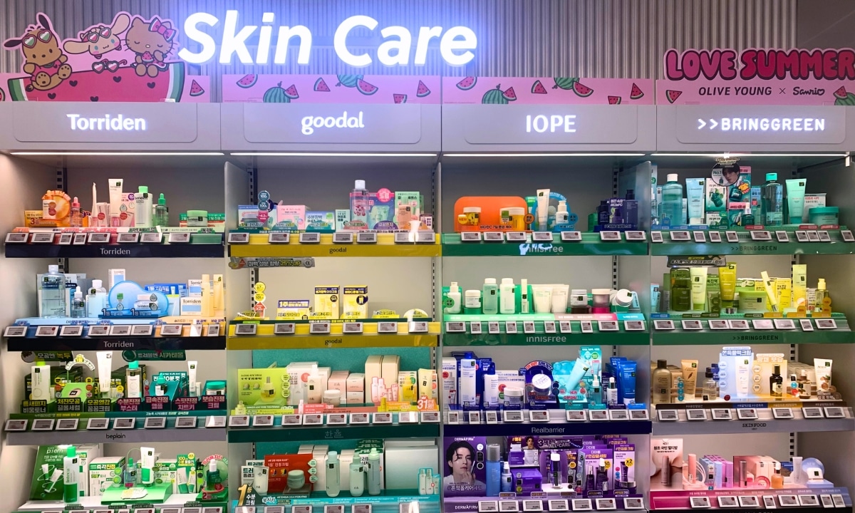Fully stocked shelf of Korean skincare products with summer essentials like aloe gel, sunblock, and cooling face masks at a beauty store.