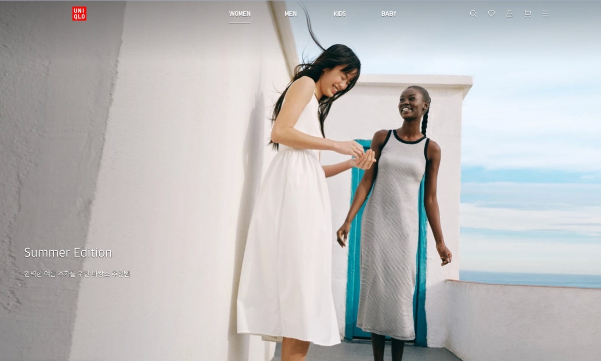 Two women wearing breezy, minimalist AIRism outfits stand near a sunny wall, showcasing UNIQLO's Korean summer clothing line for staying cool.