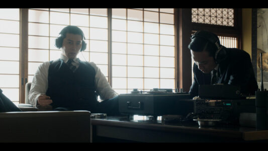 Hyun Bin in "Made in Korea" with a pair of headphones on.